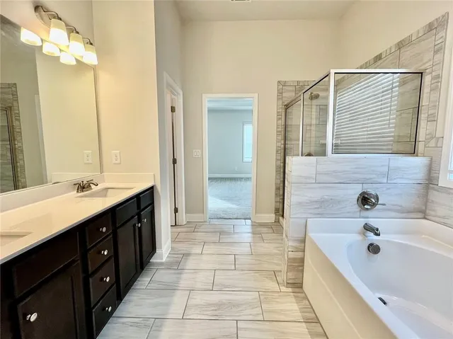 a spacious bathroom with a tub sink shower and mirror