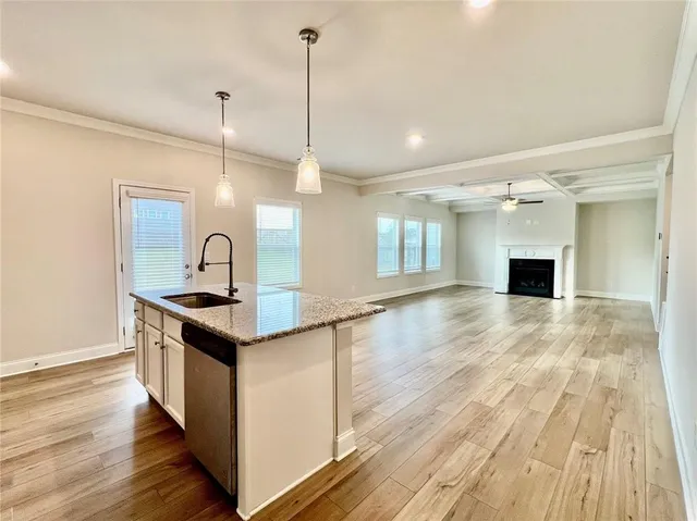 a kitchen with stainless steel appliances granite countertop a sink a stove and a wooden floors