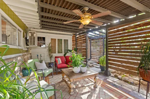 a view of a patio with table and chairs under an umbrella with a large tree