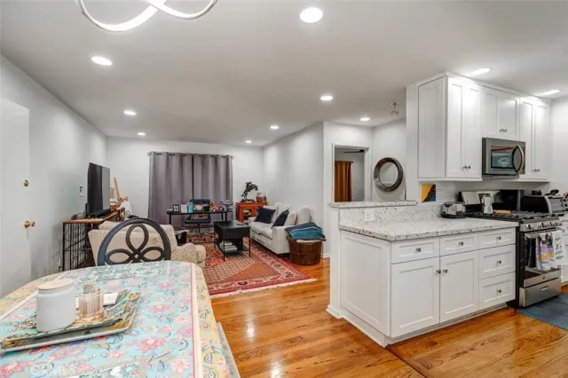 a kitchen with stainless steel appliances granite countertop a dining table chairs refrigerator and sink