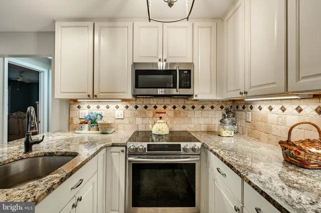a kitchen with granite countertop a sink stainless steel appliances and cabinets