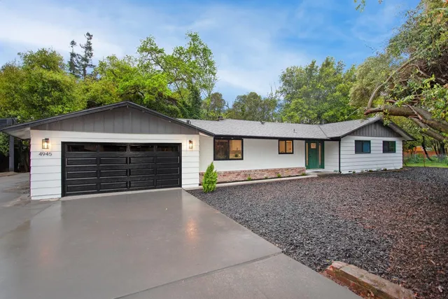 a front view of house with yard and trees in the background