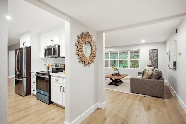 a living room with stainless steel appliances furniture and a kitchen view