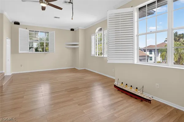 an empty room with wooden floor a ceiling fan and windows