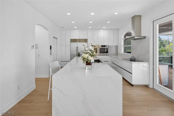 a large white kitchen with kitchen island a sink stainless steel appliances and cabinets