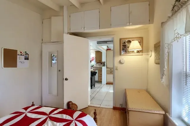 a hallway view with white cabinets and wooden floor