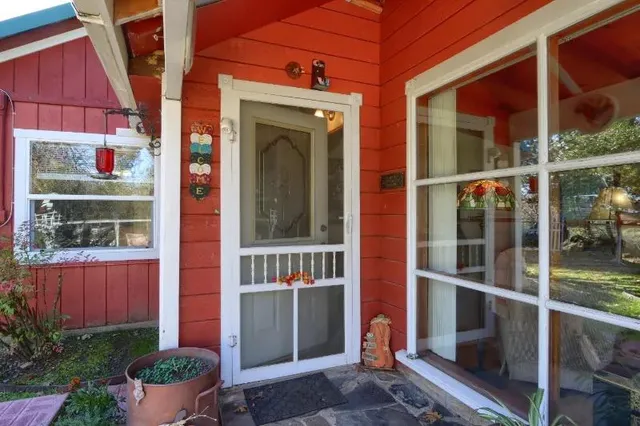 a view of small house with large windows and potted plants