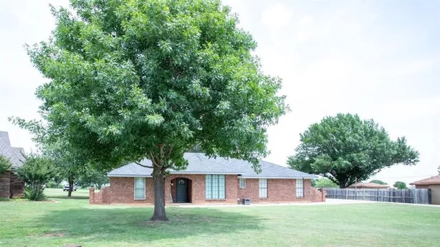 a front view of a house with a garden and trees