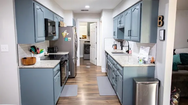 a kitchen with stainless steel appliances granite countertop lots of counter top space and wooden floor