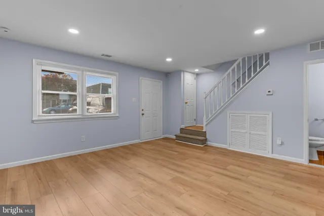 a view of empty room with wooden floor and window