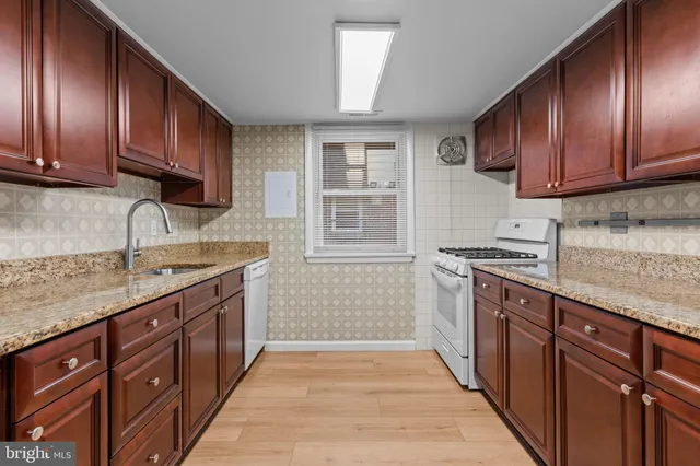 a kitchen with stainless steel appliances granite countertop a refrigerator a sink dishwasher a stove with wooden cabinets and floor