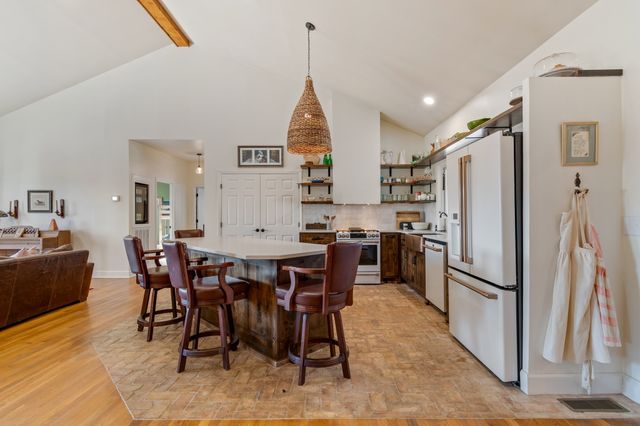 a kitchen with stainless steel appliances granite countertop a dining table chairs refrigerator and cabinets