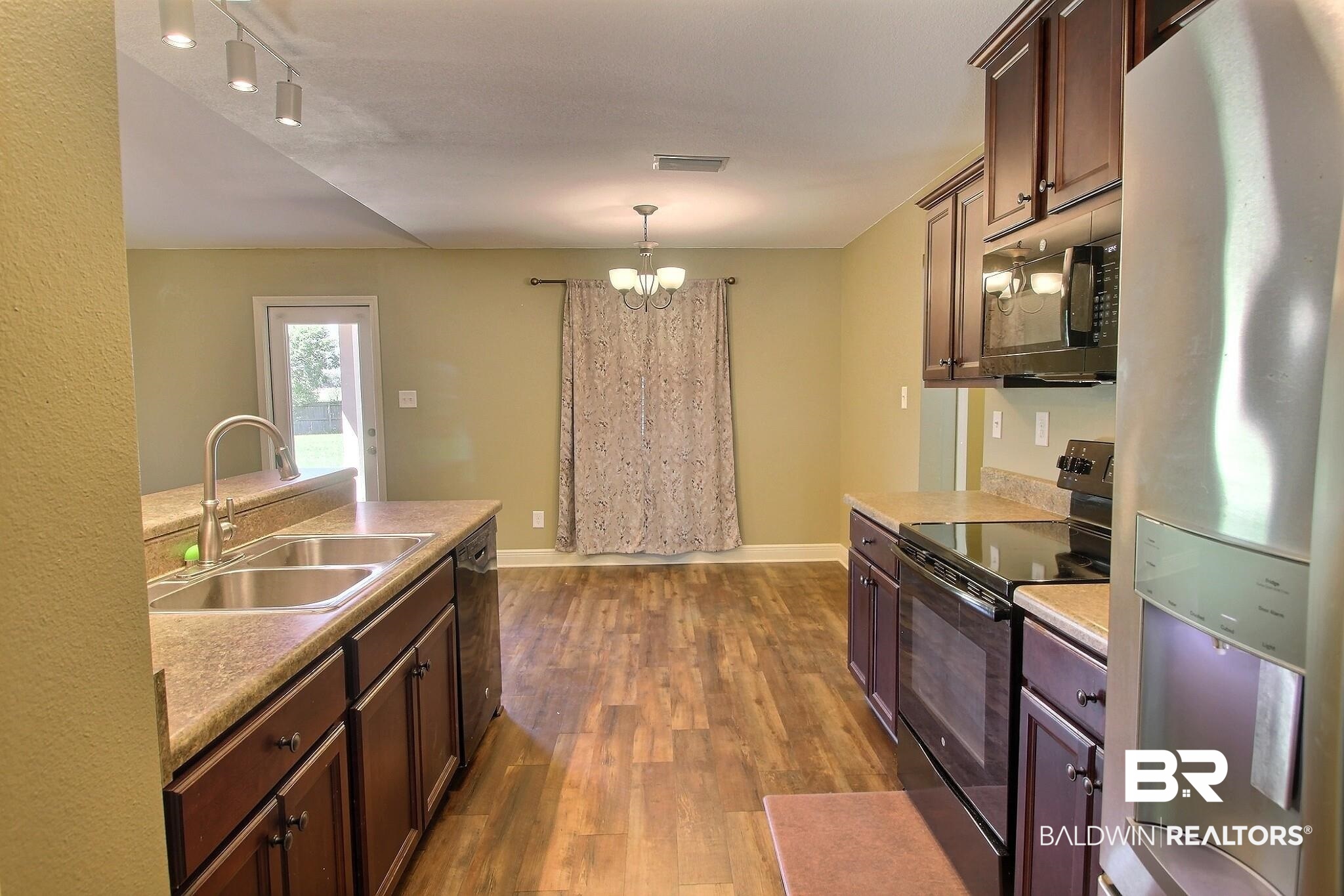 15577 Talus Court Foley, AL 36535 - Photo 7 of 28 Kitchen featuring black appliances, dark wood-type flooring, light countertops, and a chandelier