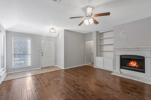 a view of an empty room with wooden floor fireplace and a window