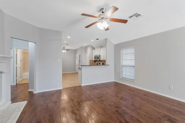 a view of an empty room with kitchen and window
