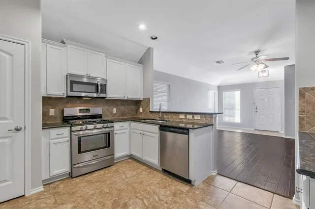 a kitchen with stainless steel appliances granite countertop a stove top oven a sink and a microwave
