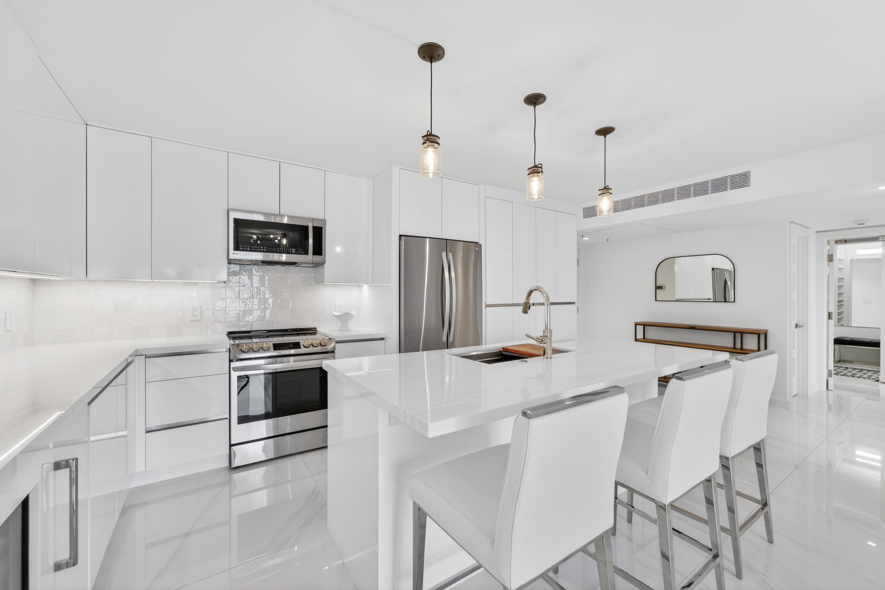 725 Hummingbird Way, Unit 103 North Palm Beach, FL 33408 - Photo 25 of 52 a kitchen with stainless steel appliances kitchen island granite countertop a stove a sink a refrigerator a stove a dining table and chairs with wooden floor