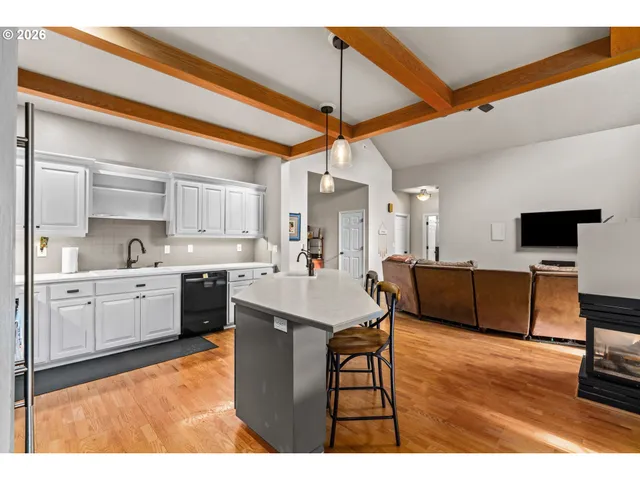 a large white kitchen with a white countertops a stove a dining table and chairs with wooden floor