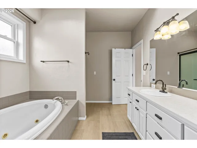 a bathroom with a tub a sink and a mirror