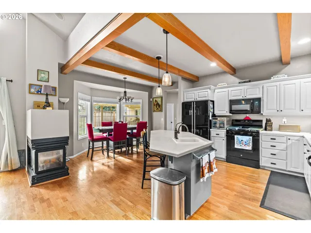 a dining hall with stainless steel appliances kitchen island granite countertop a table chairs and a refrigerator