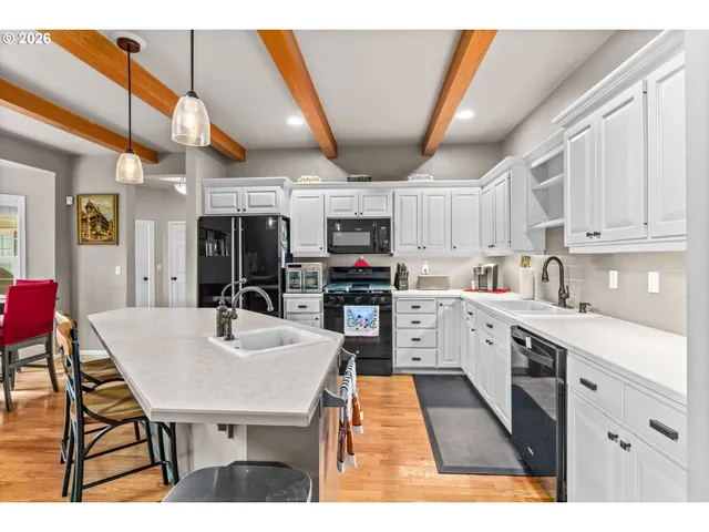 a kitchen with stainless steel appliances kitchen island granite countertop a table chairs sink and cabinets