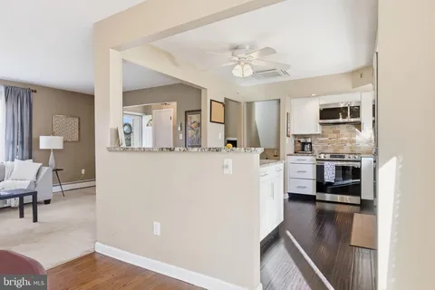 a living room with stainless steel appliances furniture a chandelier and a view of kitchen