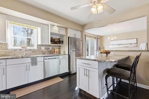 a kitchen with granite countertop white cabinets and refrigerator