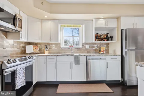 a kitchen with granite countertop white cabinets and white appliances