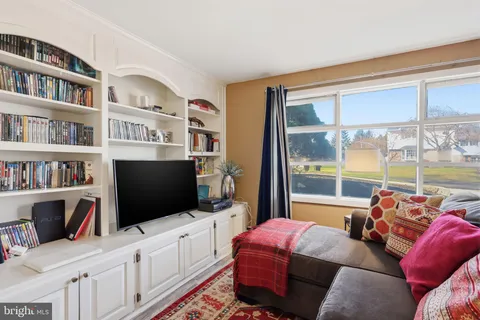 a living room with furniture a flat screen tv and a floor to ceiling window