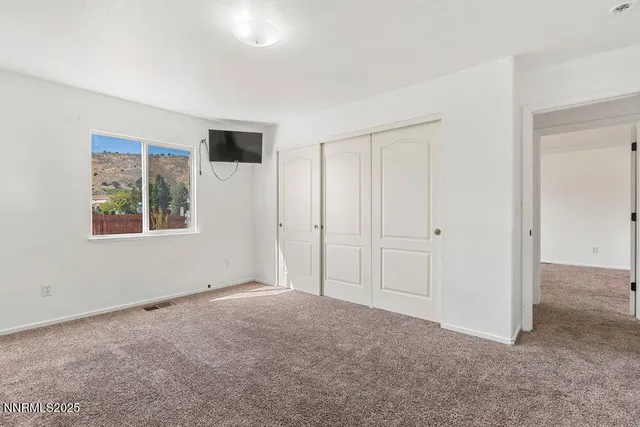 a view of an empty room with window and closet area