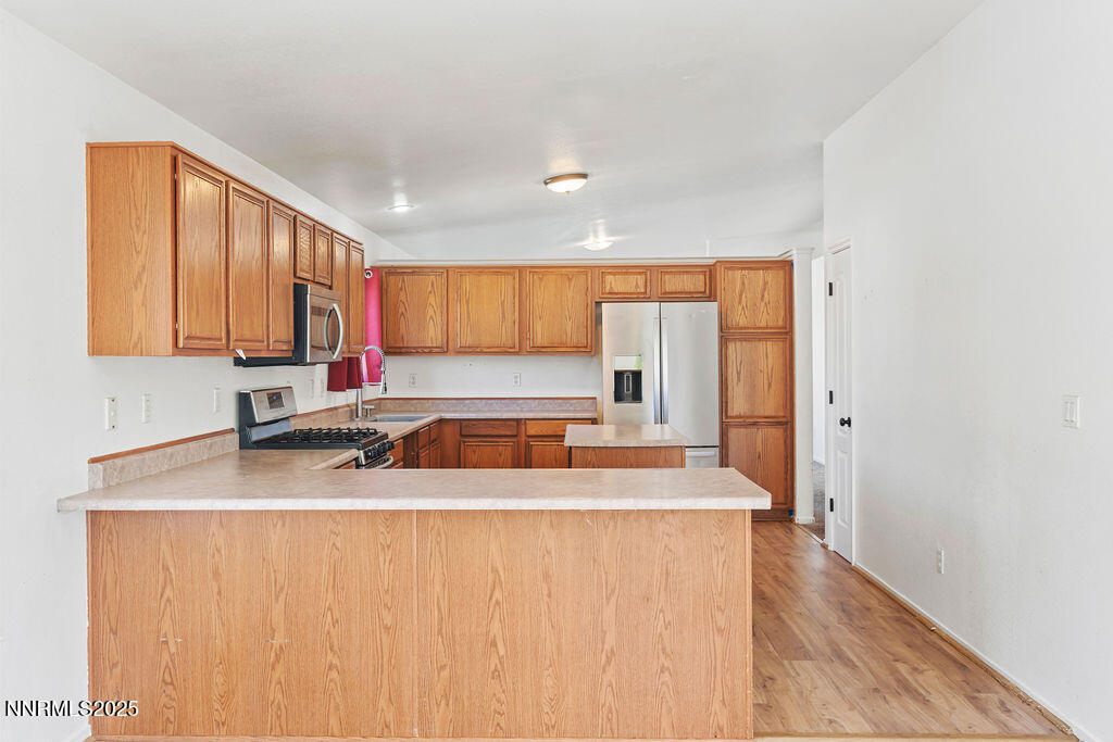 17870 Fairfax Court Reno, NV 89508 - Photo 15 of 23 a kitchen with stainless steel appliances granite countertop a sink a stove and a refrigerator with wooden floor