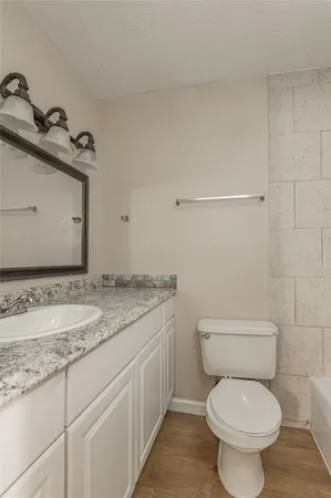 a bathroom with a granite countertop toilet a sink and a mirror