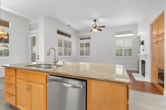 a view of a livingroom with a fireplace a ceiling fan and windows