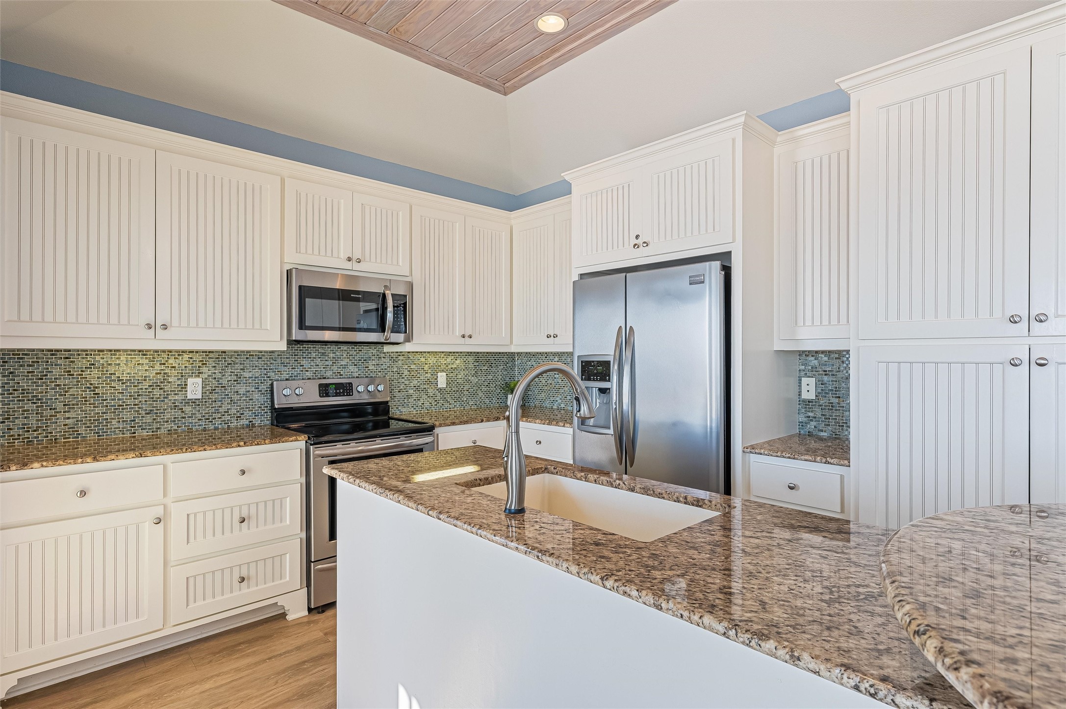 804 Eastview Crystal Beach, TX 77650 - Photo 15 of 50 a kitchen with granite countertop a refrigerator sink and white cabinets