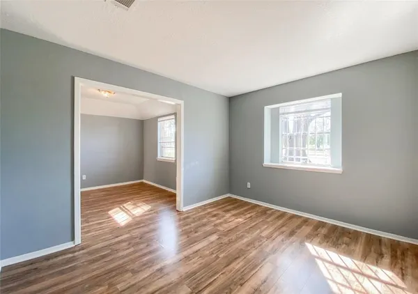 a view of wooden floor in an empty room with a window