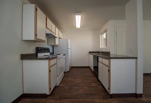 a kitchen with granite countertop white cabinets and white appliances