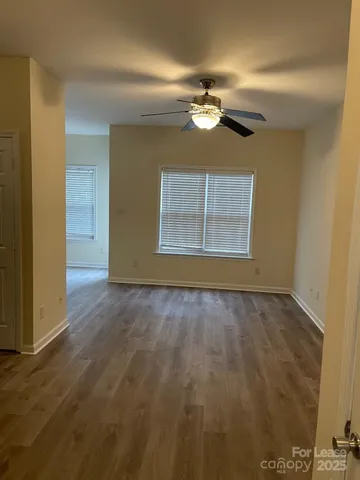 an empty room with a chandelier fan and windows