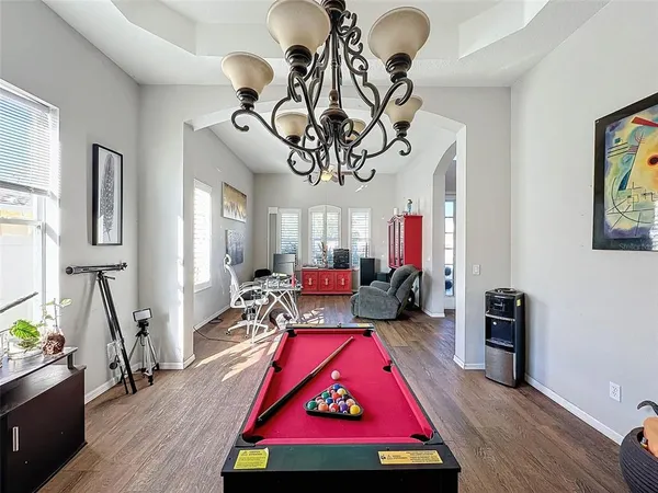 a living room with couches a fireplace and a dining table with wooden floor
