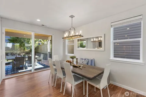 a dining room with wooden floor a chandelier a wooden table and chairs