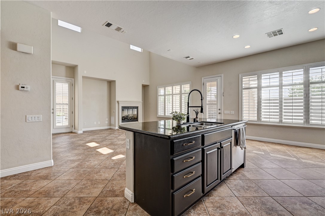 2793 Rosenhearty Drive Henderson, NV 89044 - Photo 16 of 85 An open-concept living space with a kitchen island and fireplace offers a comfortable, versatile environment.