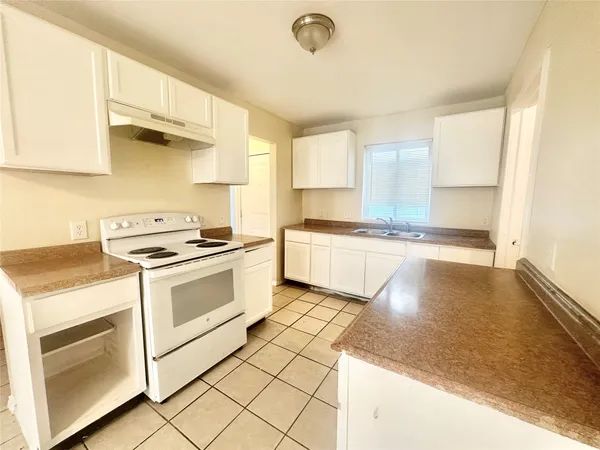 a large white kitchen with a stove a sink dishwasher and a refrigerator