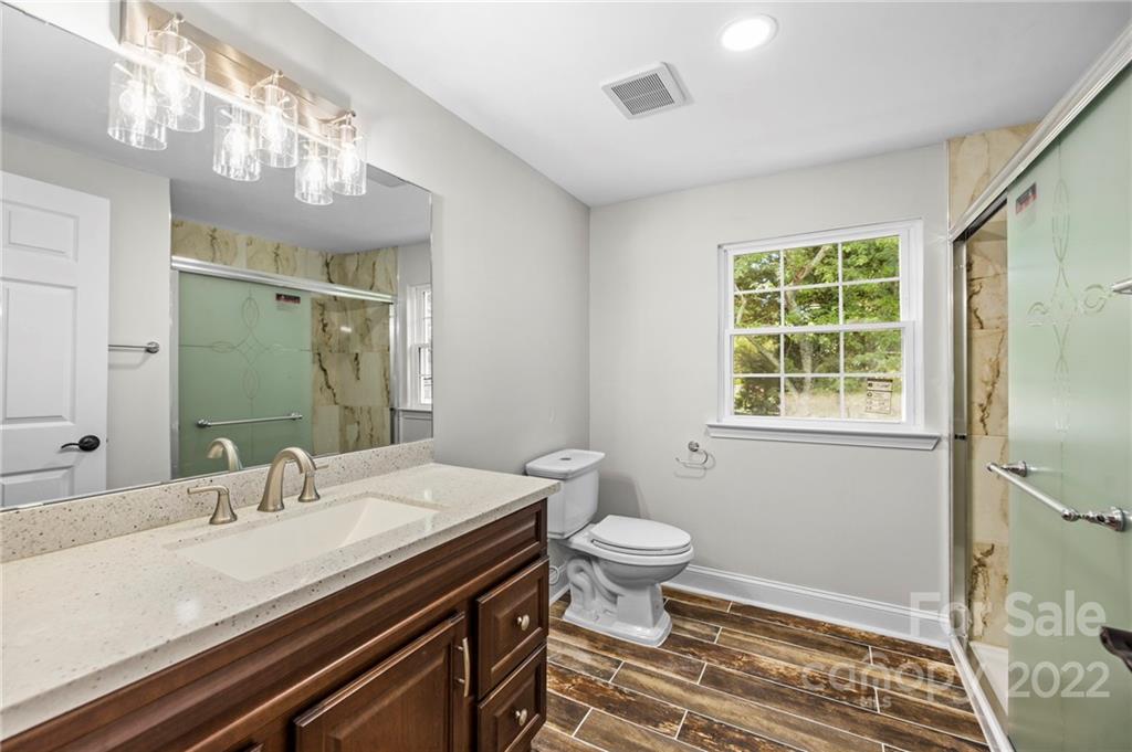 6000 Hickory Grove Road Charlotte, NC 28215 - Photo 37 of 40 a bathroom with a sink a toilet a mirror and a window