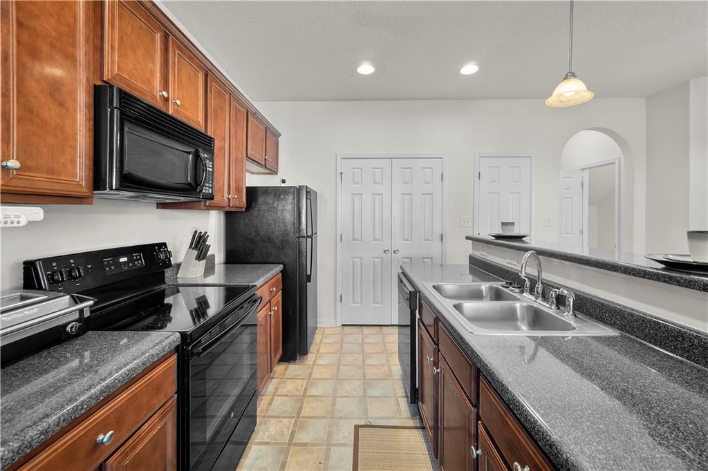 6120 Capitol Knoll Fairburn, GA 30213 - Photo 10 of 28 a kitchen with stainless steel appliances granite countertop a sink a stove top oven a refrigerator cabinets and a wooden floor
