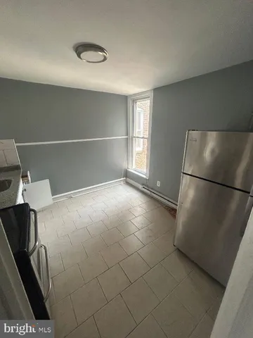 a view of a refrigerator in kitchen and an empty room