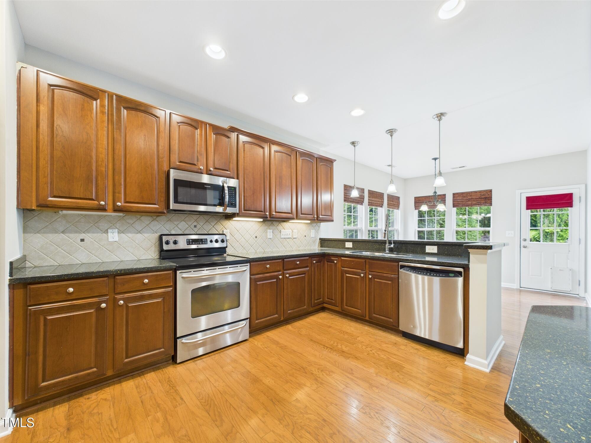 12589 Honeychurch Street Raleigh, NC 27614 - Photo 15 of 100 a kitchen with stainless steel appliances granite countertop wooden cabinets a stove top oven a sink and dishwasher