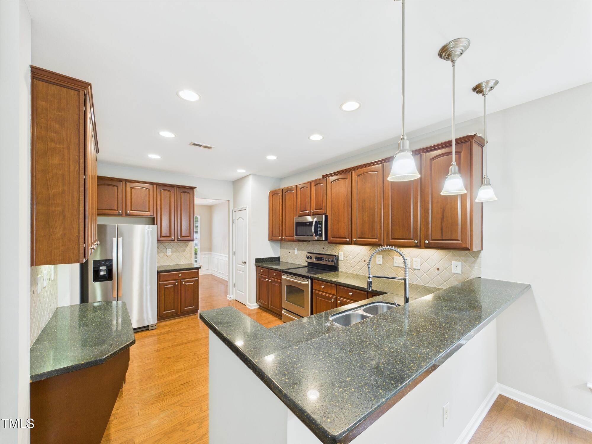 12589 Honeychurch Street Raleigh, NC 27614 - Photo 16 of 100 a kitchen with stainless steel appliances granite countertop a sink a stove and a refrigerator