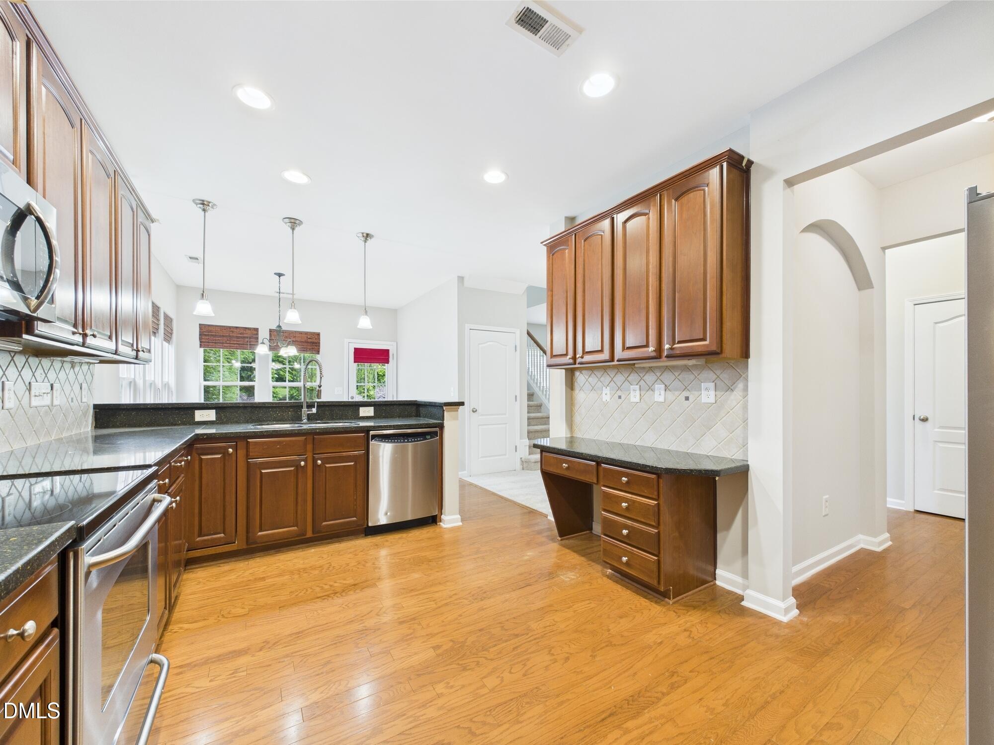 12589 Honeychurch Street Raleigh, NC 27614 - Photo 68 of 100 a kitchen with stainless steel appliances granite countertop a stove a sink and a microwave