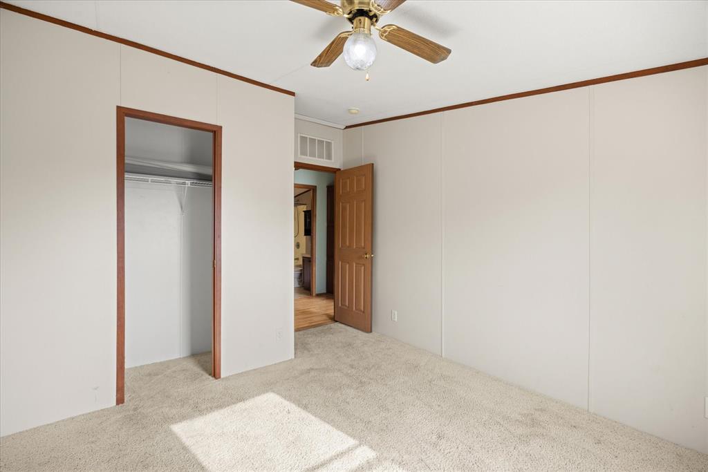 2903 Centaurus Way Granbury, TX 76048 - Photo 12 of 31 Unfurnished bedroom featuring crown molding, light colored carpet, a ceiling fan, a closet, and a decorative wall