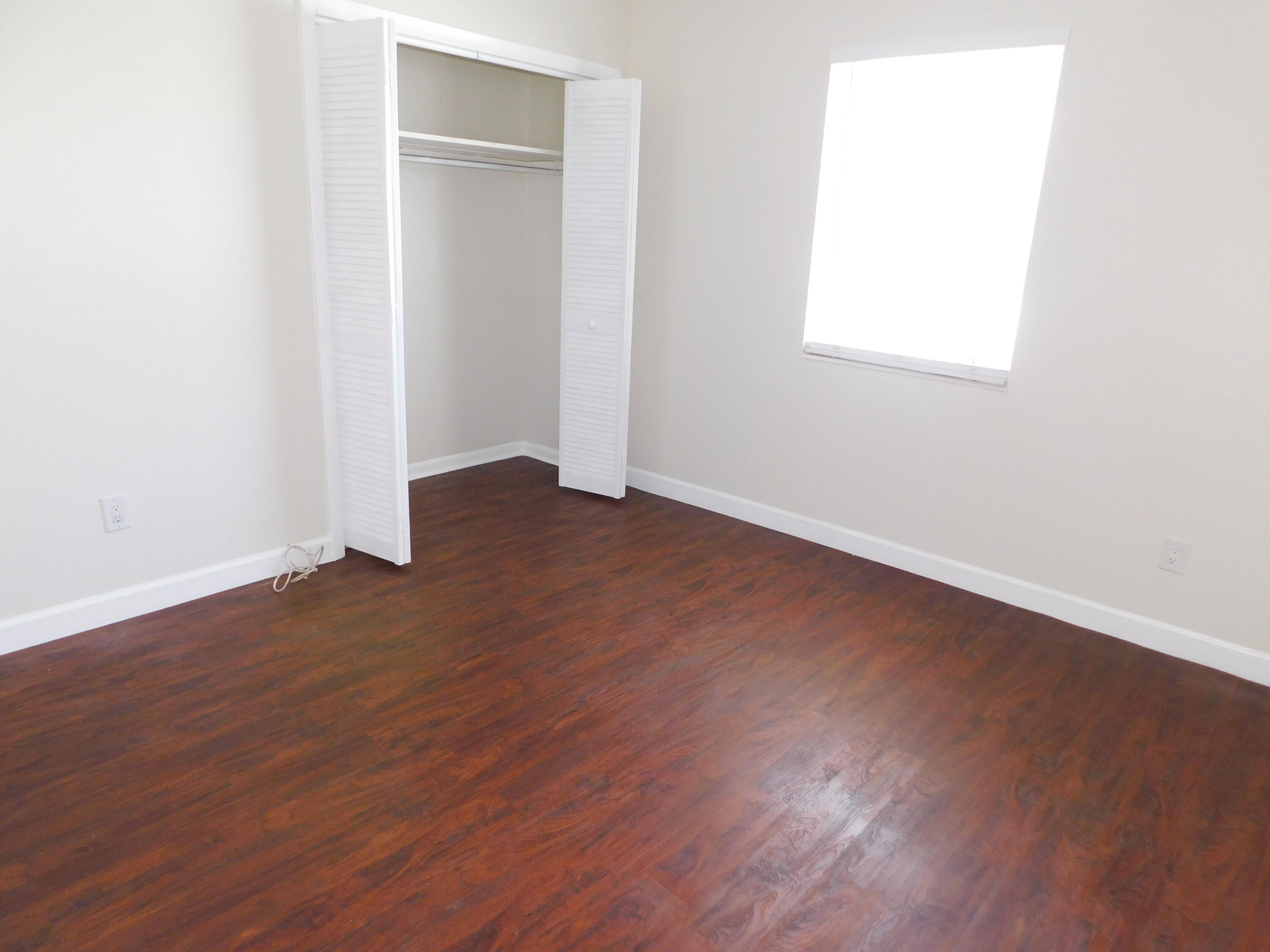 741 Hummingbird Way, Unit 4 North Palm Beach, FL 33408 - Photo 12 of 19 an empty room with wooden floor and windows