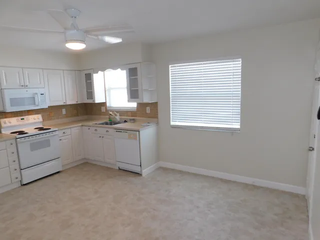 a kitchen with granite countertop white cabinets and white appliances